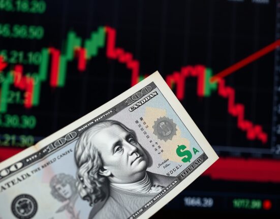 Canadian and US dollar banknotes on a trading desk with a downward-trending chart in the background