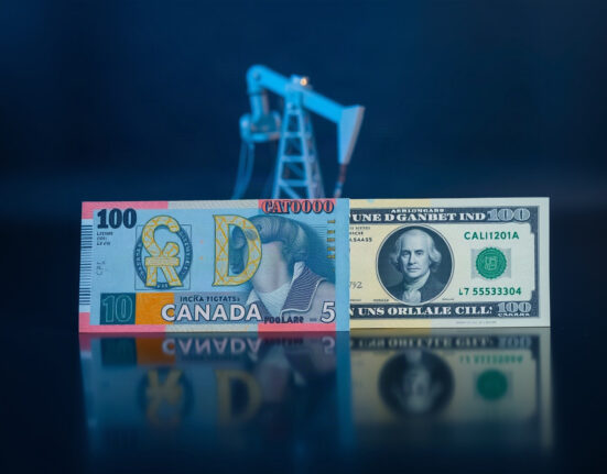 Canadian and US dollar banknotes with oil derrick in background, symbolizing currency pressure from oil and tariffs.