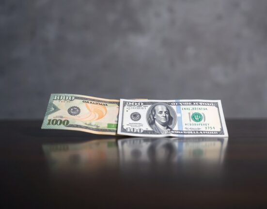 Canadian and US dollar banknotes on a dark surface representing forex trading analysis.