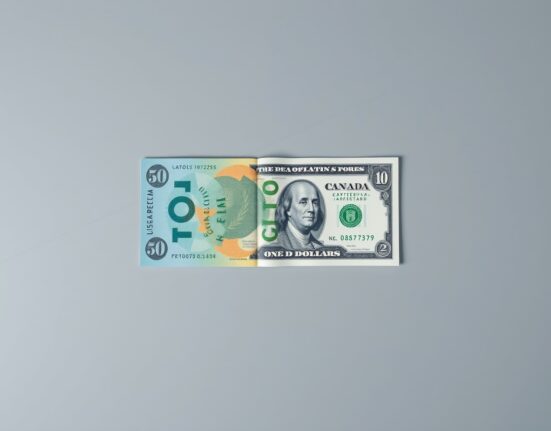 Canadian and US dollar banknotes on a surface with a blurred financial chart background