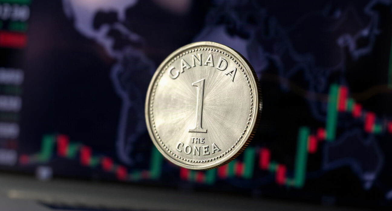Canadian dollar coin (Loonie) with blurred financial charts in background