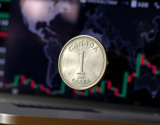 Canadian dollar coin (Loonie) with blurred financial charts in background