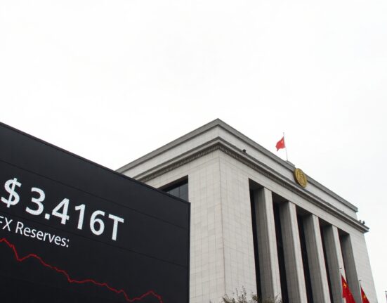 Exterior view of the People's Bank of China headquarters with an electronic display showing foreign exchange reserve data.