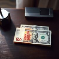 Chinese yuan and US dollar banknotes on a desk, representing forex market trends.