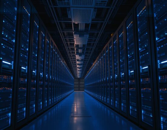 Interior of a large, modern data center with rows of server racks illuminated by blue and amber lights.