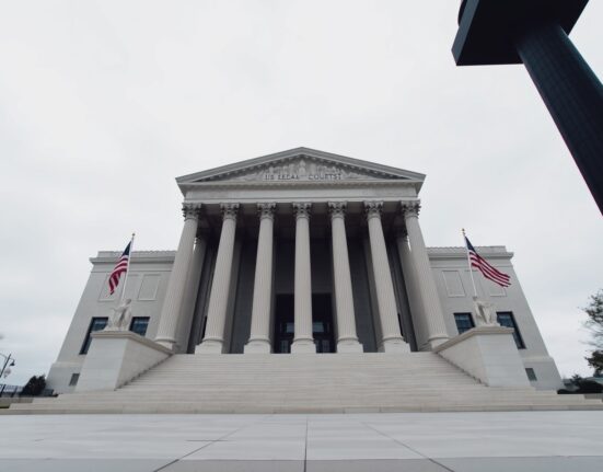 Exterior of a US federal courthouse with columns and flags, symbolizing legal proceedings.