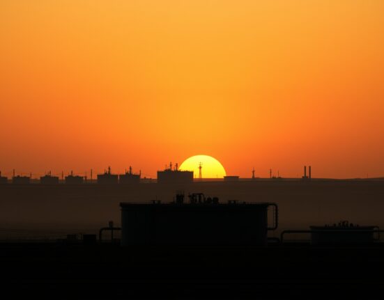 Empty oil storage tanks at sunset symbolizing declining crude oil demand and fading geopolitical risk premium.