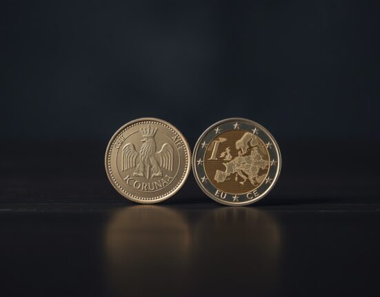 Czech koruna coin next to euro coin on dark surface