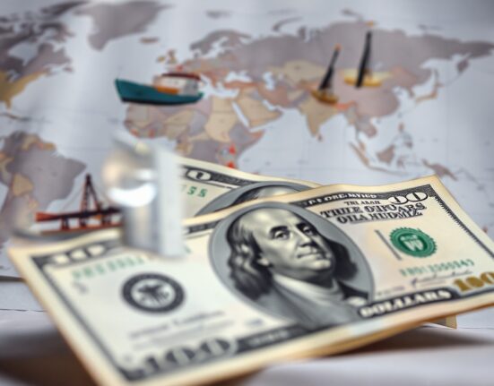 US dollar banknotes with a map and shipping imagery in the background, symbolizing currency markets and geopolitical risk.