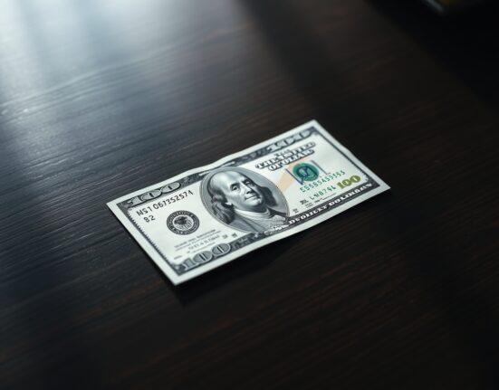 US dollar bill on desk with financial chart showing a downward trend, representing currency market reaction to inflation data.