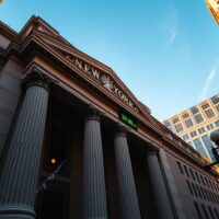 New York Stock Exchange building with digital ticker showing Dow Jones index in green
