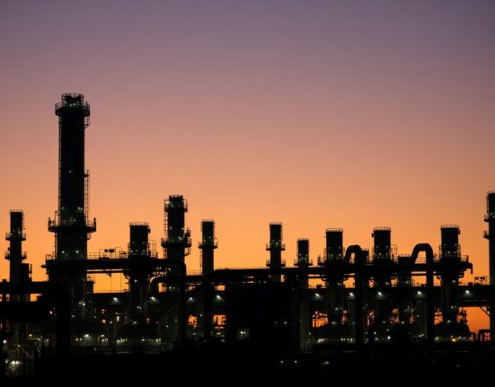 Oil refinery at dusk with towers and pipes, symbolizing refining margins and war premium in fuel markets