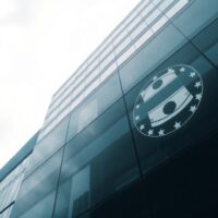 European Central Bank headquarters in Frankfurt on a cloudy day, with oil barrel reflection symbolizing rate hike risk.