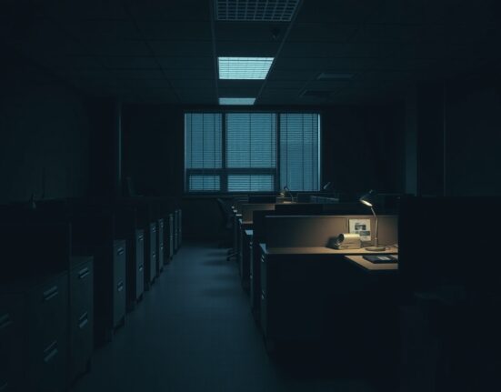 Darkened nearly empty office of Catze Labs after ESPORTS token crash with single lit desk