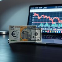 Euro and US dollar banknotes on a desk with a financial chart in the background