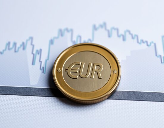 Euro coin on financial charts representing analysis of currency strength and monetary policy.