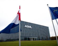 Exterior of ASML headquarters in Veldhoven, Netherlands, with Dutch and EU flags in foreground.