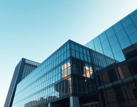 Exterior of a modern glass corporate headquarters in a financial district under a clear blue sky