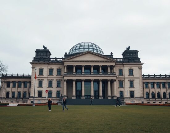 Exterior view of the German Bundestag (Reichstag) building in Berlin on a cloudy day, representing parliamentary decision-making on crypto tax policy.