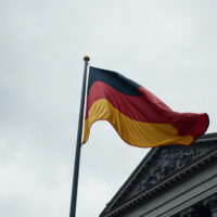 German flag in front of Reichstag, symbolizing economic uncertainty from Iran conflict.