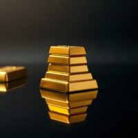 Stack of polished gold bars on a dark reflective surface, representing gold price stability above $4,300.