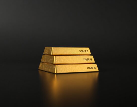 Close-up of stacked gold bars with dark background and soft lighting for financial news article.