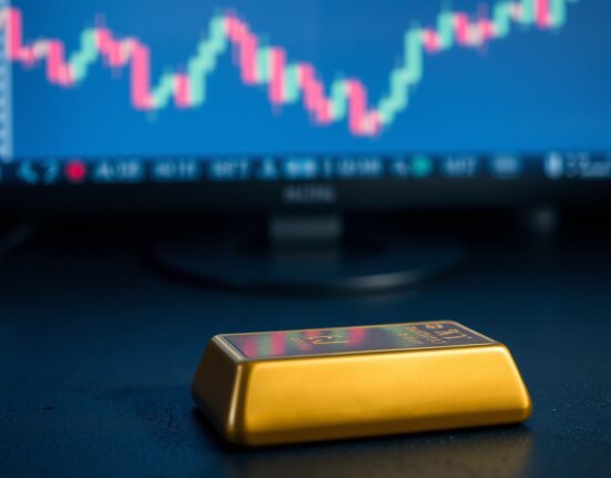 Gold bar with blurred chart showing downward trend in background