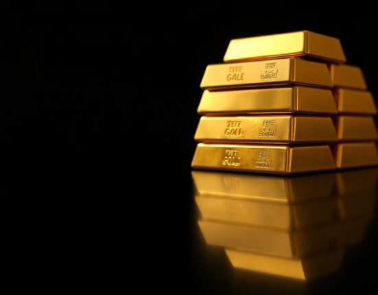 Stacked gold bars on a dark surface representing precious metals market consolidation above $4,300.