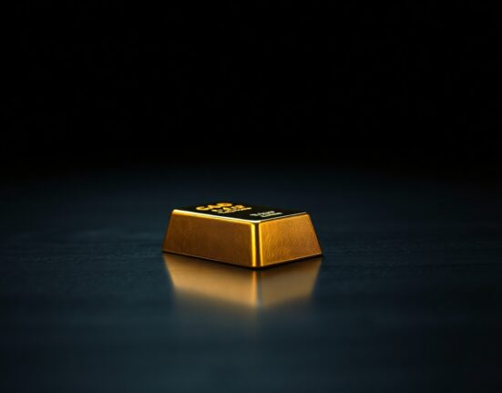 Gold bar on dark wooden surface representing declining precious metal prices