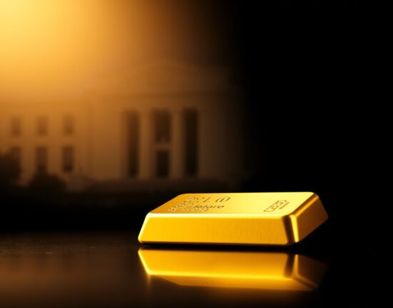 A gold bar illuminated on a dark surface with a faint silhouette of the Federal Reserve building in the background.