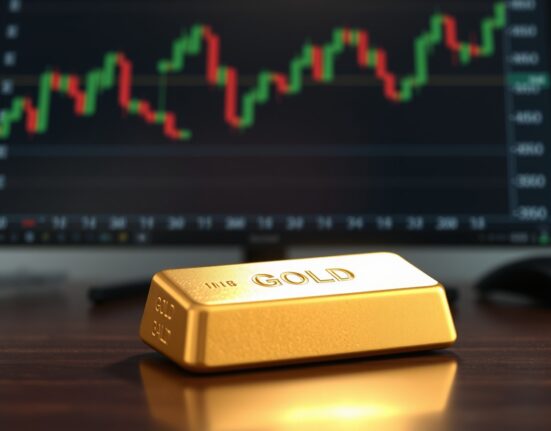 Gold bar on a wooden surface with a financial chart in the background.