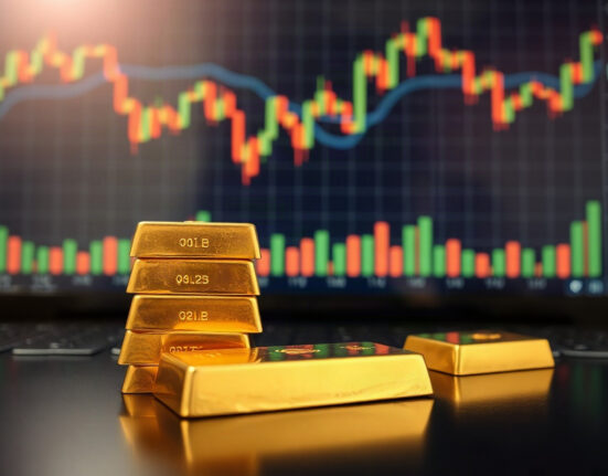 Gold bullion bars on a dark surface with a financial chart in the background