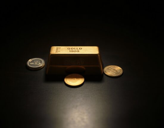 Gold bars and coins on a dark surface representing precious metals market volatility.