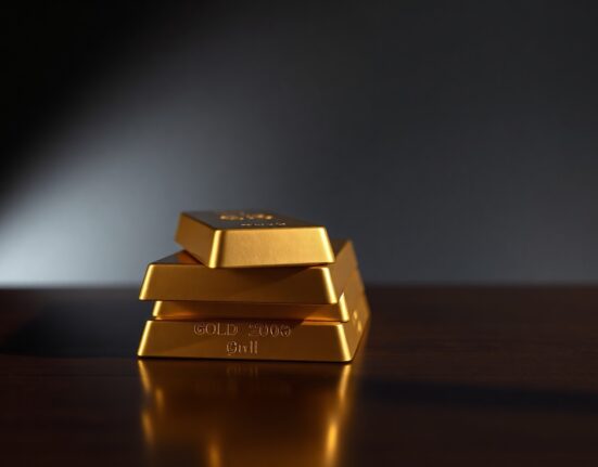 Stack of gold bullion bars on dark surface representing precious metals market amid inflation concerns