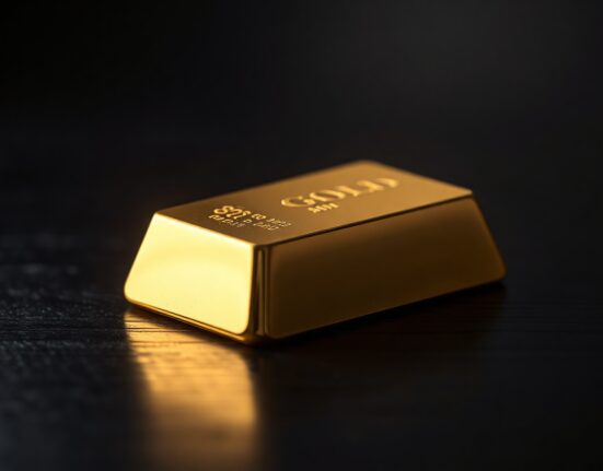Close-up of a gold bar on a dark surface, representing precious metal prices under pressure.