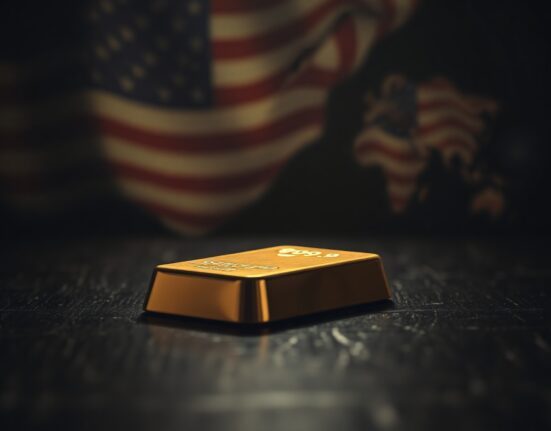 Gold bullion bar on dark surface with US flag and world map in background, representing market tension.