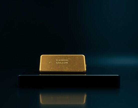 Gold bullion bar on dark surface with soft lighting, representing falling precious metal prices.