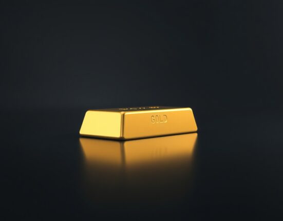 Gold bar on dark reflective surface representing precious metals market analysis
