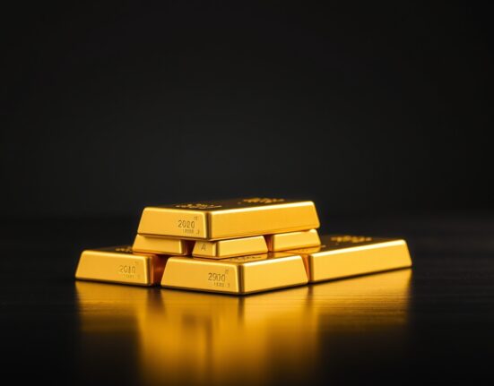 Close-up of stacked gold bars on a dark surface, representing falling gold prices in India.