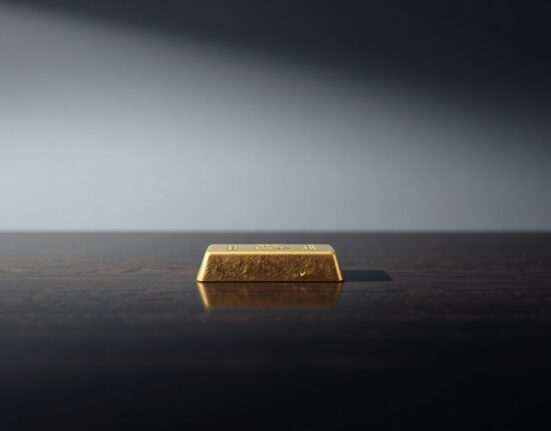 A single gold bar on a dark wooden surface, representing gold market forecasts.