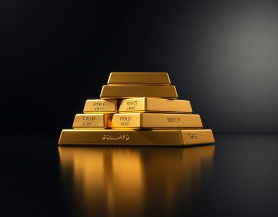 Stack of gold bullion bars on reflective surface with dramatic lighting