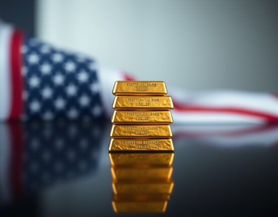 Stacked gold bars with soft lighting and American flag bokeh in background.