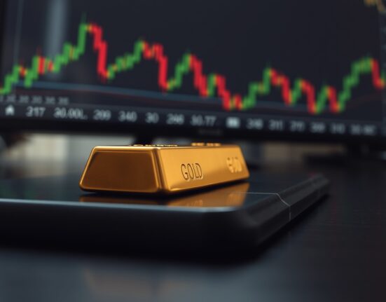 Gold bar on wooden surface with financial charts in background