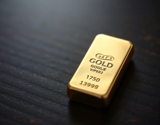 Close-up of a gold bar on a dark wooden surface with soft lighting, representing gold price vulnerability amid Fed rate expectations.