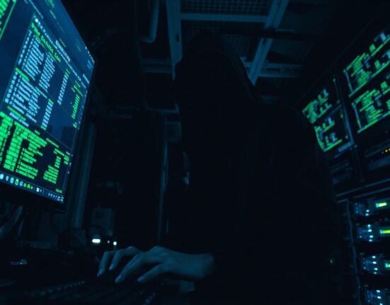 Hooded figure in a dark server room using a computer to launder cryptocurrency through Tornado Cash