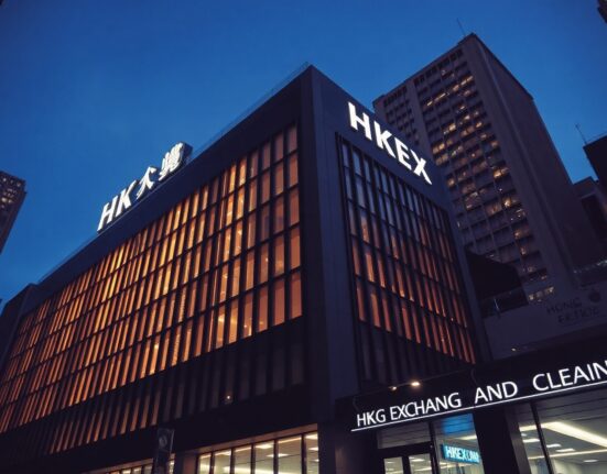Exterior view of the Hong Kong Exchanges and Clearing building in a financial district at dusk.