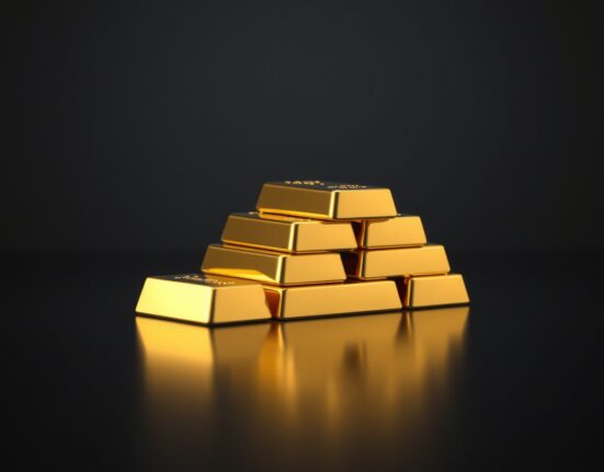 Stack of polished gold bars on a dark reflective surface, representing the latest gold price increase in India.