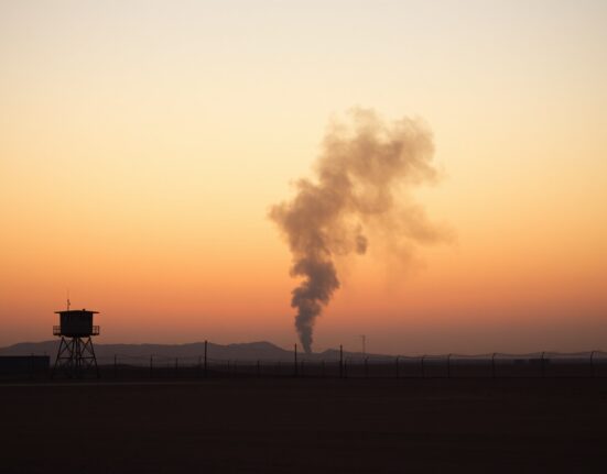 Smoke rising over a desert military base in Kuwait at dusk