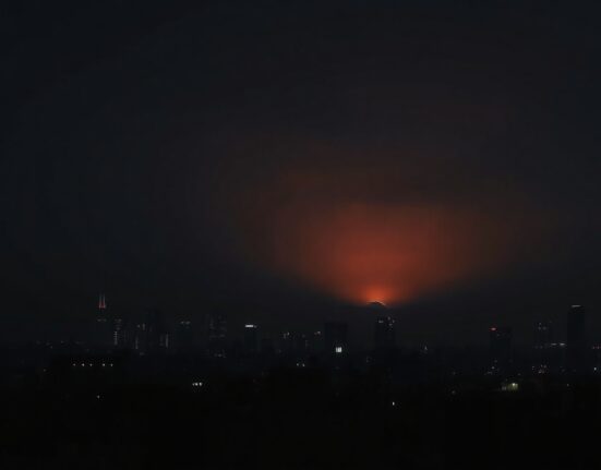 Night skyline of Tehran with faint orange glow on horizon after reported strikes