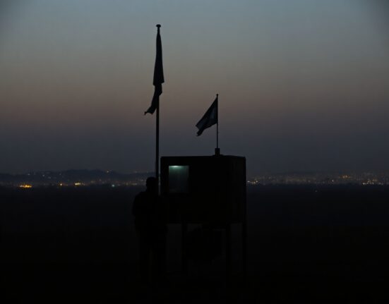 Military checkpoint silhouette at dusk with distant city smoke, representing Iran-Israel tensions